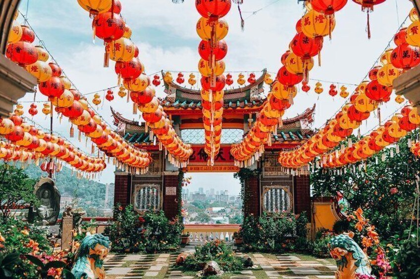 A traditional Chinese gate adorned with red lanterns and surrounded by lush greenery. 1