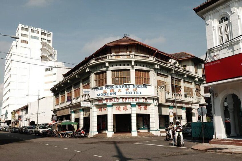 A historic building with signage for 'RUMAH PENGINAN PAN MODERN HOTEL' and 'THE WORLD OPTICAL CO.' 3