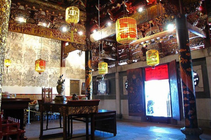 An ornate interior with traditional lanterns, intricate wall murals, and a large red door. 2