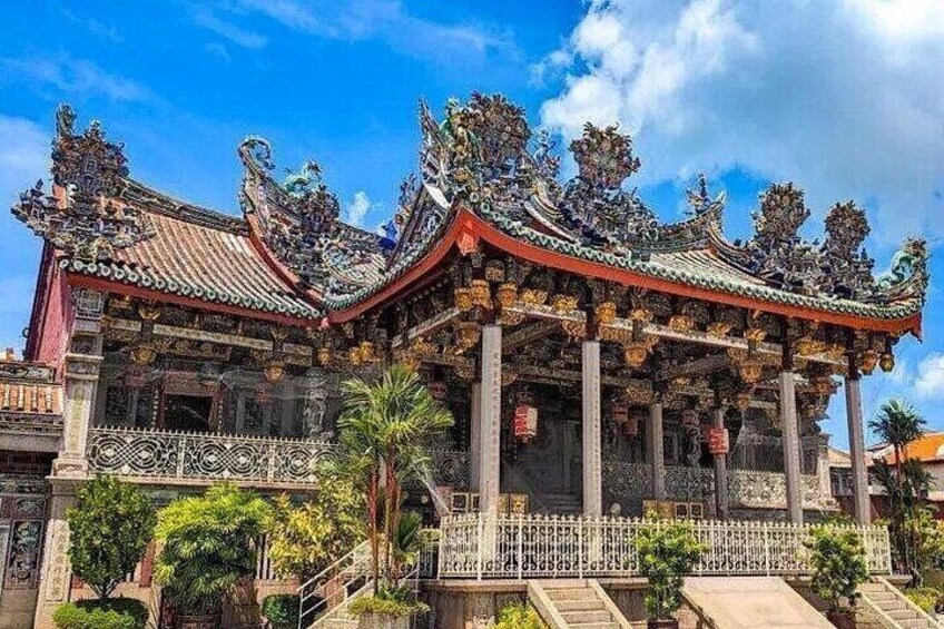 Een traditionele tempel met versierde architectuur, een ruime centrale hal en een omliggende tuin. 1