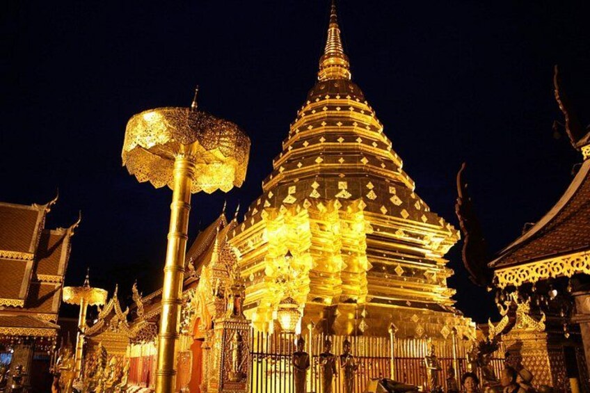 A golden temple with intricate designs and a pointed spire, surrounded by traditional architecture. 1