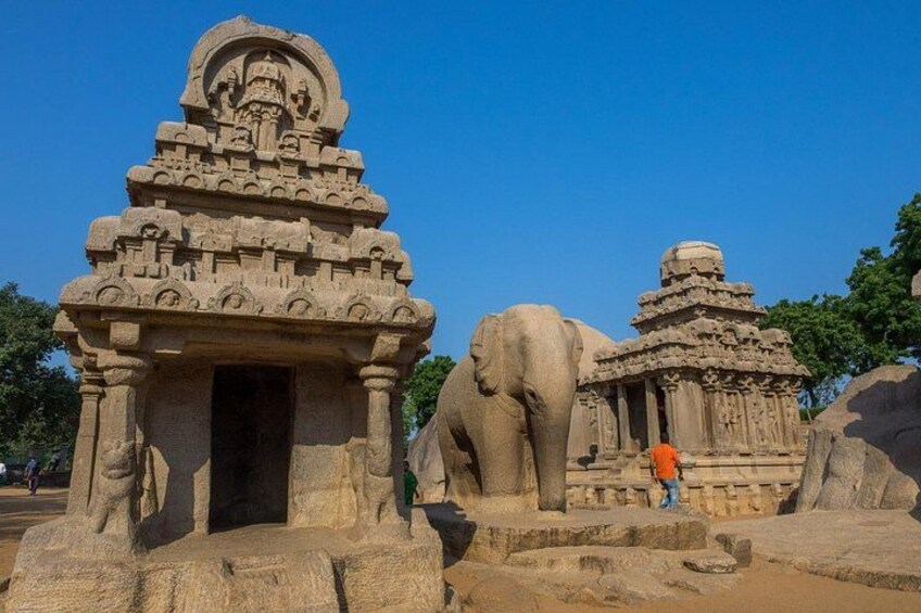 A sandstone temple with intricate carvings, a large elephant statue, and a smaller structure with a dome. 4