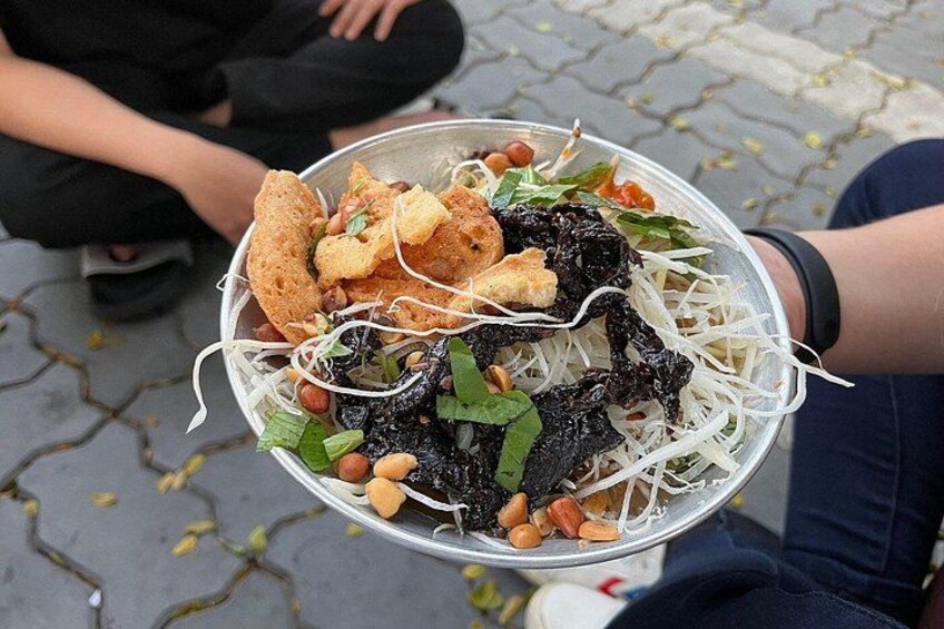 Een persoon houdt een kom noedels met diverse toppings. 2