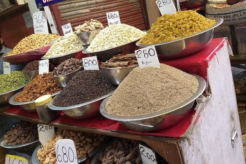 A variety of nuts and seeds displayed in metal bowls with price tags. 2