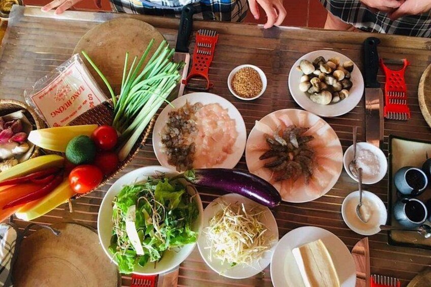Una mesa con diversos alimentos y condimentos, entre ellos verduras, setas y un plato de carne en rodajas. 3