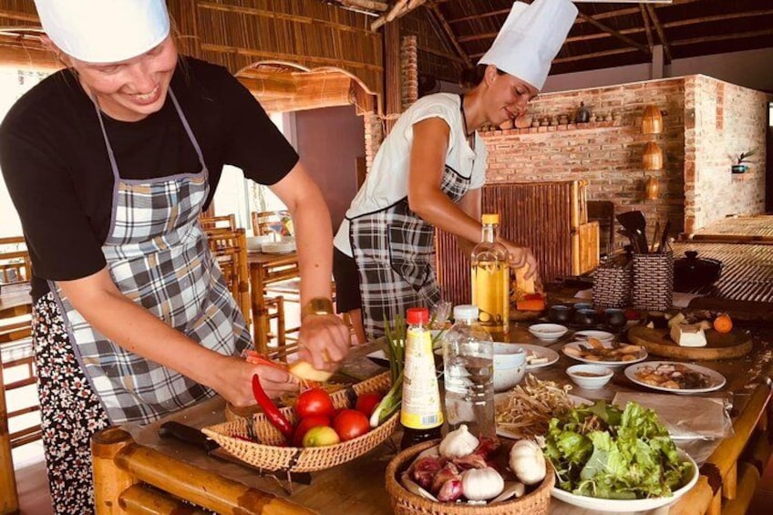 Köche bereiten Essen in einer rustikalen Küche mit Holztischen und Backsteinwänden zu. 2
