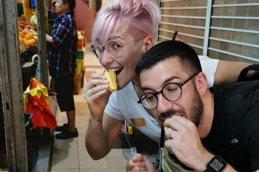 Two people eating ice cream at a market stall. 1