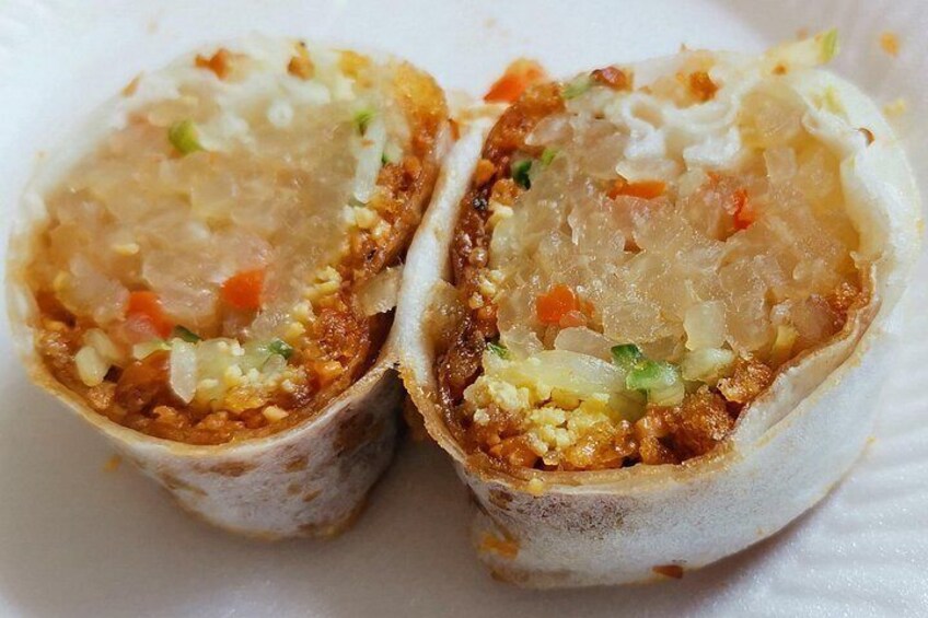 A food item, possibly a type of wrap, cut in half to reveal its contents. 5