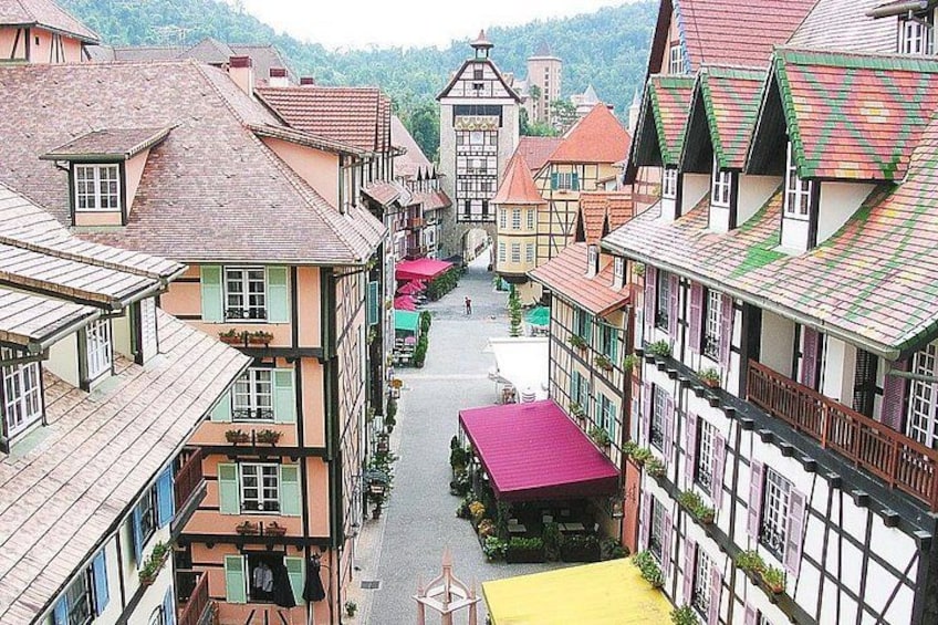 A narrow street lined with traditional half-timbered houses, a central building with a bell tower, and a yellow awning. 2