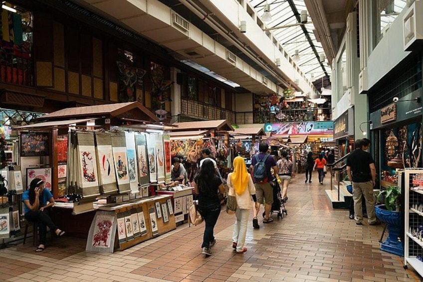 An indoor market with stalls selling various goods, people walking, and a high ceiling with skylights. 2