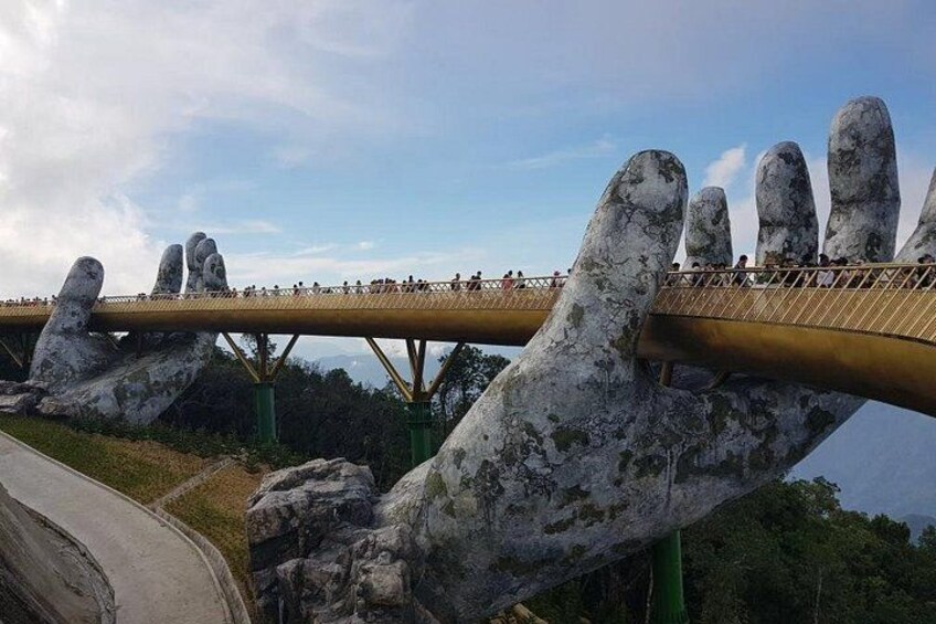 A bridge with a unique hand-shaped design, a road, and a forested landscape. 5