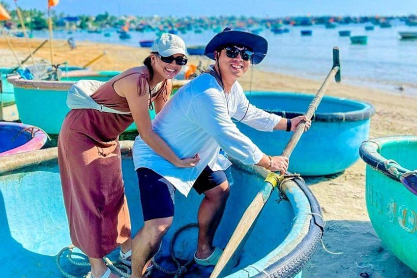 Two people in a boat on a beach with multiple boats and a clear sky. 2