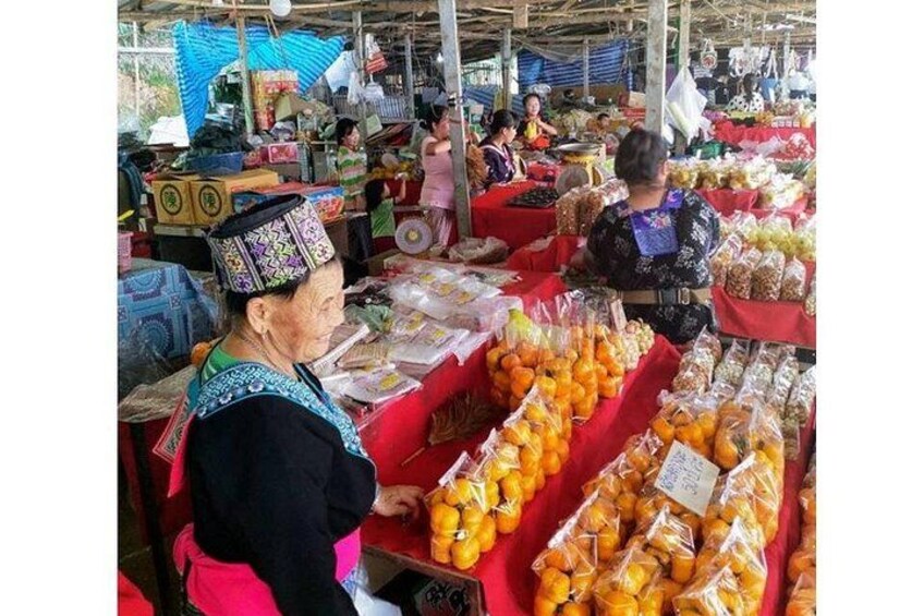 A market with people and tables displaying fruits and vegetables. 2
