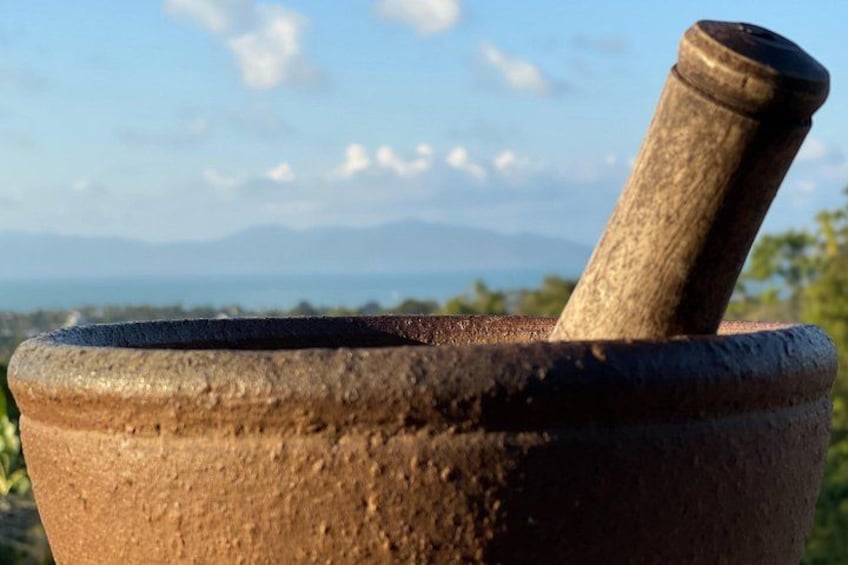 A stone mortar with a pestle, set against a backdrop of mountains and a clear sky. 2