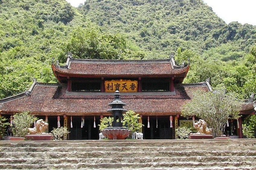 A traditional Chinese temple with a tiled roof, a central pagoda, and stone lions at the entrance. 5