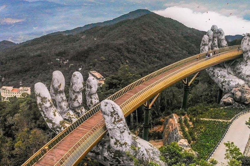 A bridge with a unique design resembling a hand, set against a mountainous backdrop. 1