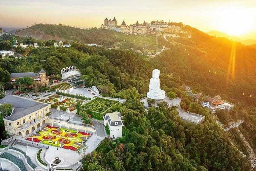 A large white statue on a hill, surrounded by buildings and a castle in the background. 4