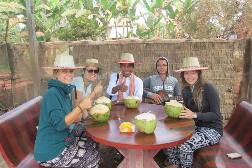 A group of people sitting around a table with coconuts and a banana. 2