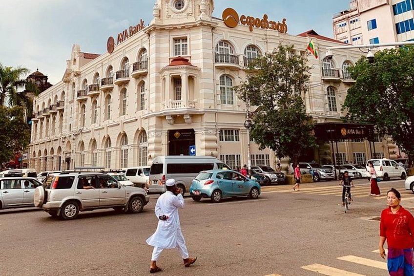A busy street with a large building labeled 'AYA Bank' and a pedestrian crossing. 3