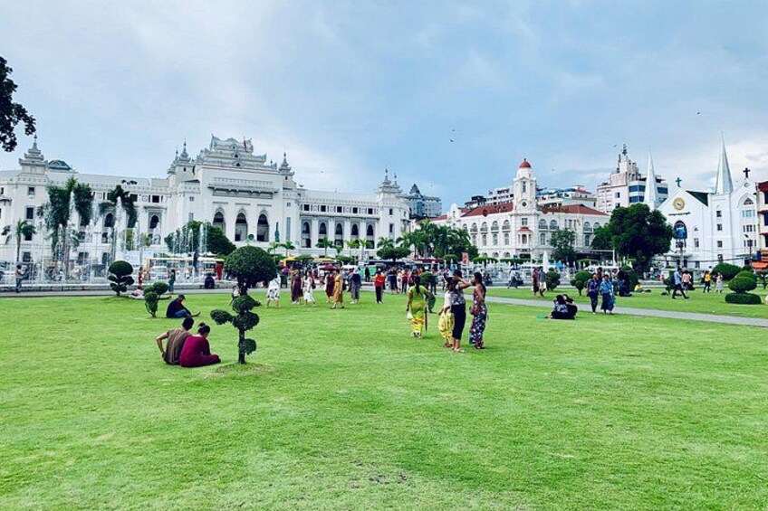 A large open grassy area with people, a fountain, and historic buildings in the background. 2
