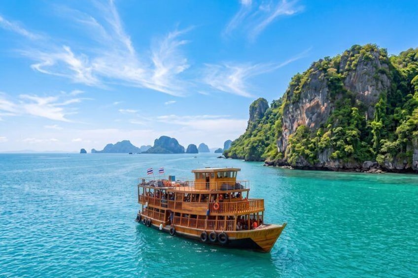A wooden boat on turquoise water with a rocky island in the background. 1