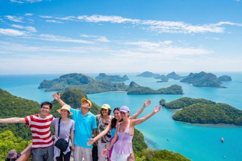 A group of people on a cliff overlooking turquoise waters and green islands. 2