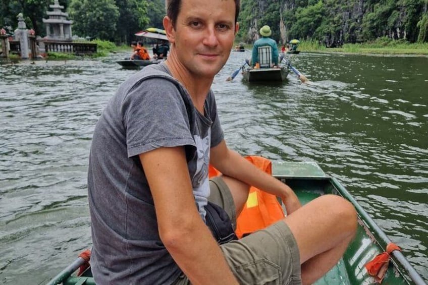 Een persoon in een groene boot op een rivier, met een andere boot op de achtergrond. 3