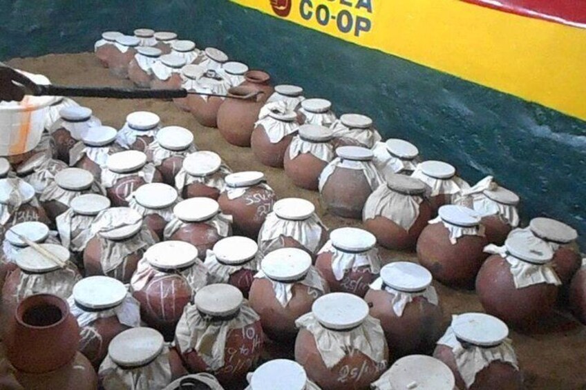 Numerous clay pots with lids, some wrapped in cloth, arranged on the ground. 3
