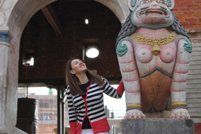 A person standing next to a large, colorful statue with a bell. 4