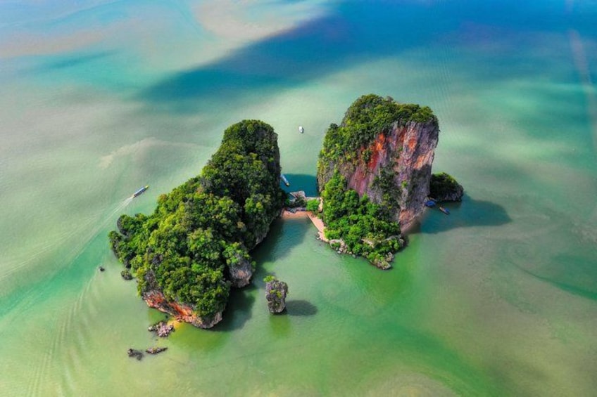 An aerial view of a lush, green island surrounded by clear turquoise waters. 3