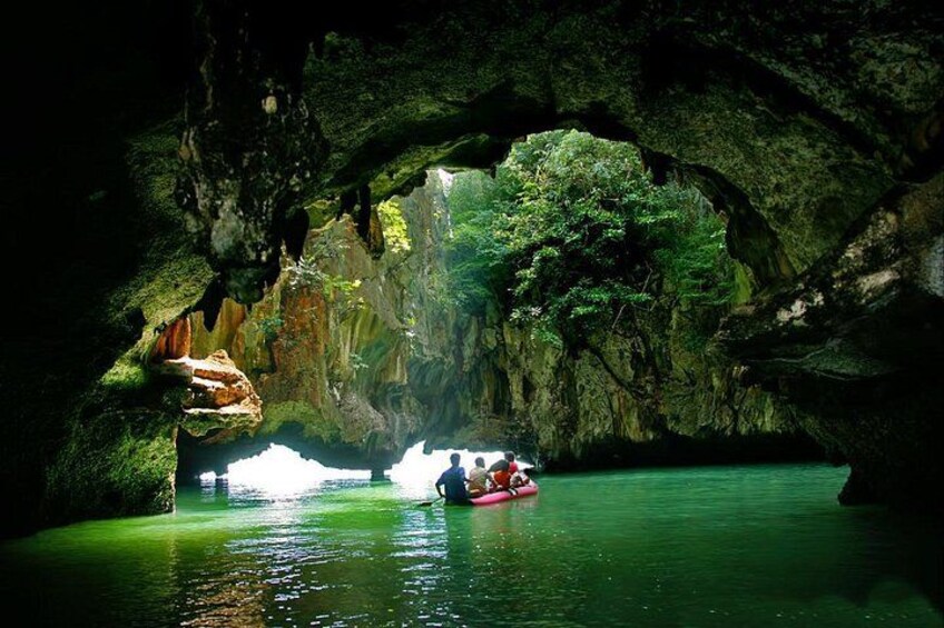 A cave with a water body, a person in a red kayak, and a natural rock formation. 2