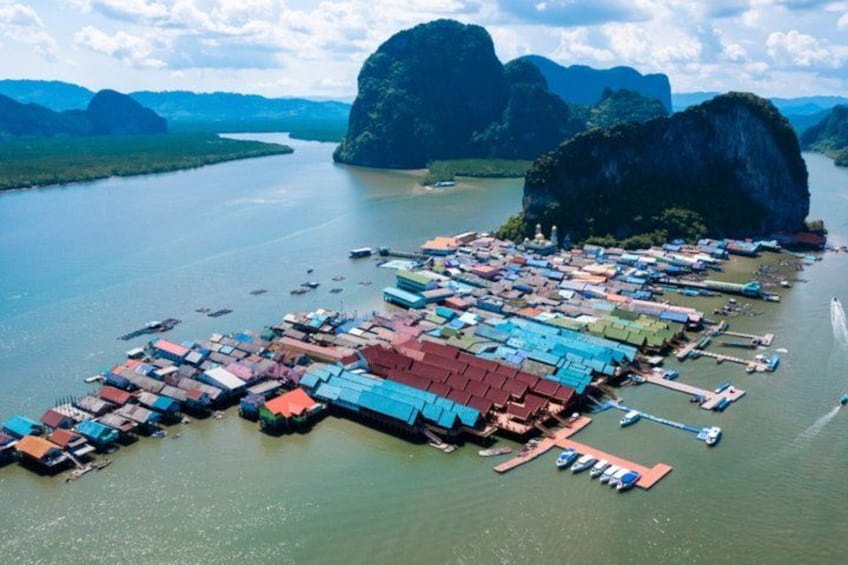 Un village flottant composé de nombreuses embarcations et de maisons sur pilotis, construites au-dessus de l’eau et entourées d’imposants reliefs karstiques calcaires. 3