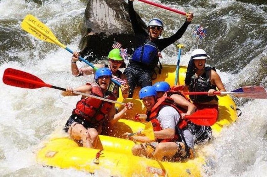 A group of people in a yellow raft navigating a river. 2