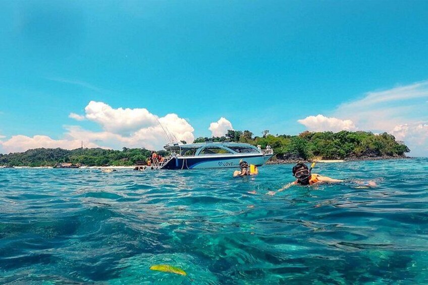 Un bateau sur l’eau, des gens qui nagent et un ciel bleu dégagé. 3