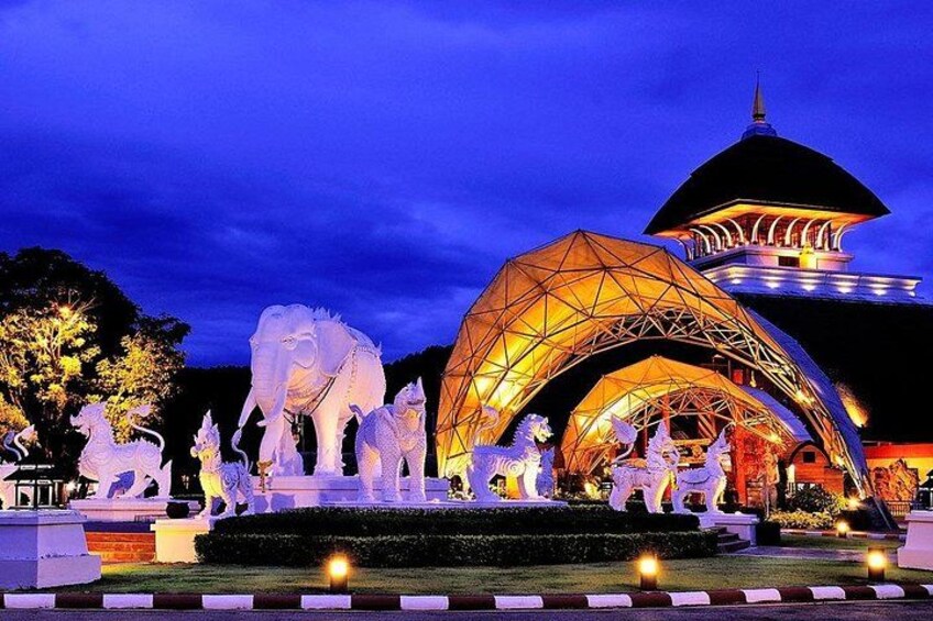 A night scene with illuminated sculptures of elephants and horses, a large dome structure, and a pagoda-like building. 3