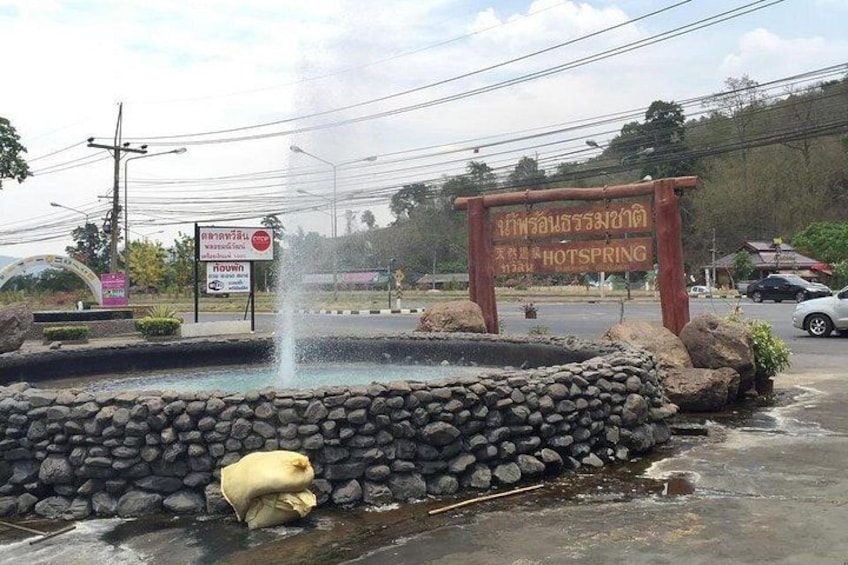 A fountain, a stone wall, and a sign with Thai text. 4