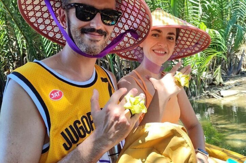Une personne portant un débardeur jaune avec le mot « JUGO » écrit dessus, tenant une fleur jaune, et une autre personne portant un chapeau de paille. 4
