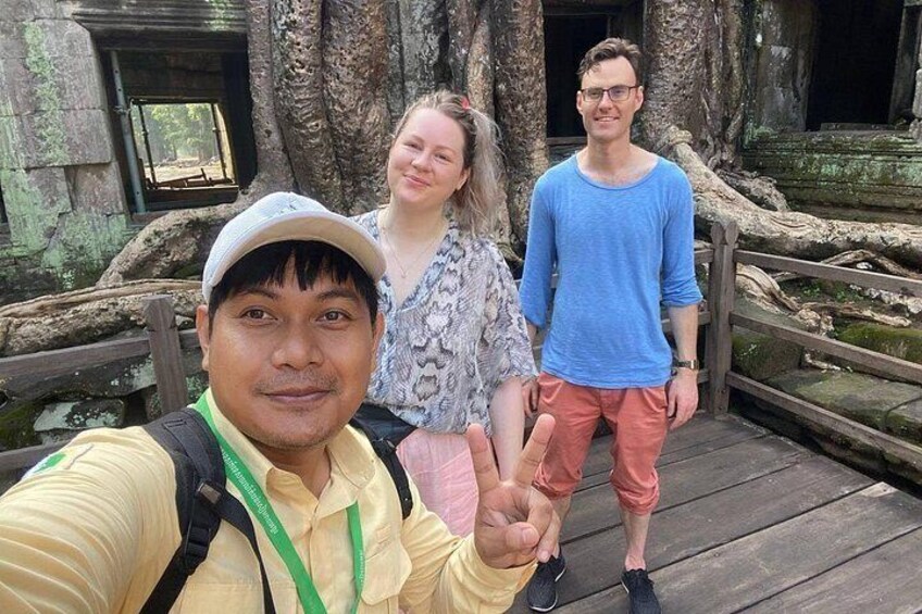 Three people on a wooden bridge with trees and a wooden railing in the background. 5