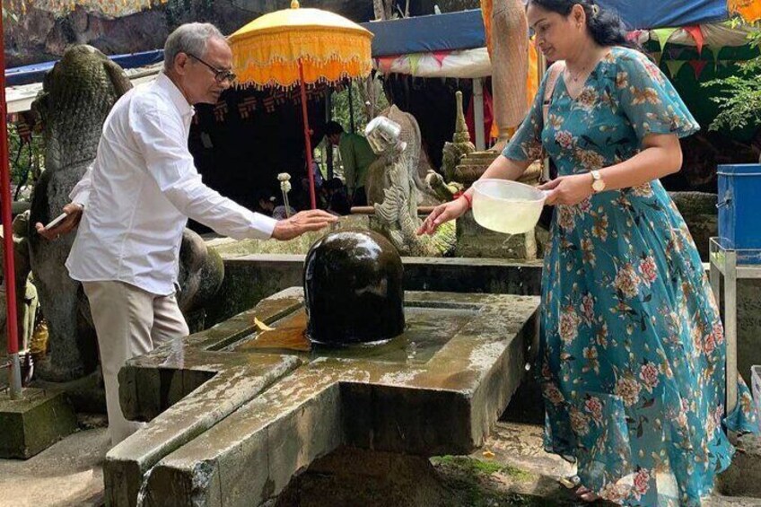 A man and a woman at a temple, performing a ritual with a water container. 2
