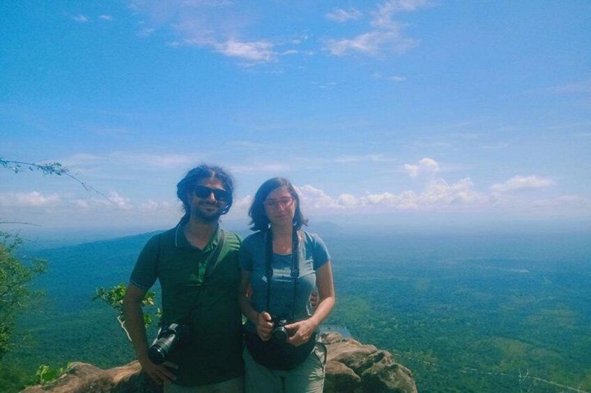 Zwei Personen stehen auf einer felsigen Klippe mit Blick auf eine weite Landschaft. 4