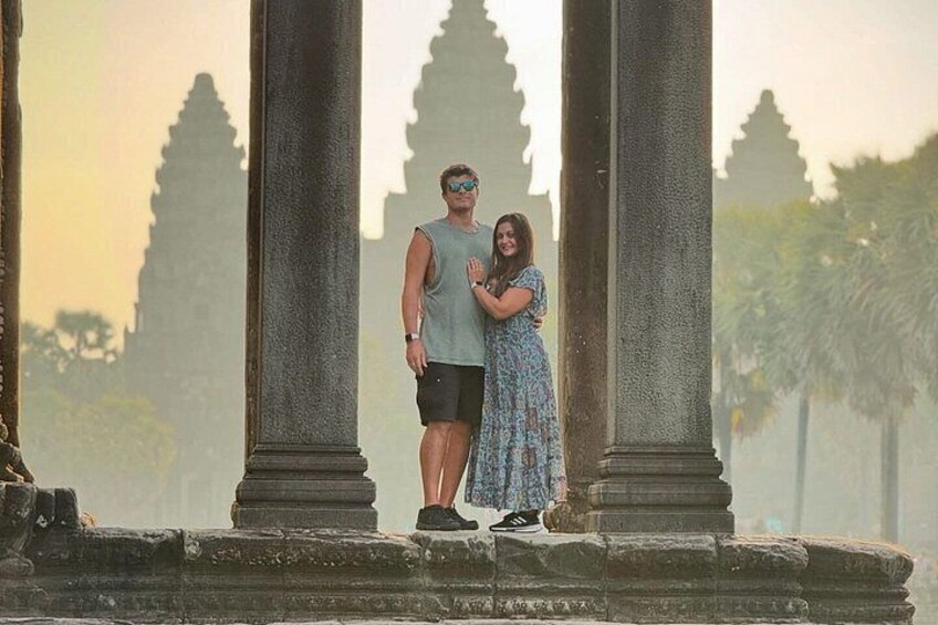Un couple se tient devant d’anciennes colonnes de pierre, avec un temple en arrière-plan. 5
