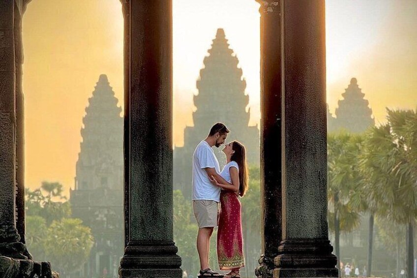 Un couple s’embrasse devant les colonnes d’un temple antique, avec un coucher de soleil en arrière-plan. 2