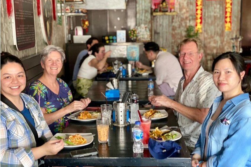 Un groupe de personnes est réuni dans un restaurant, autour d’une table où sont servis différents plats et boissons. 4