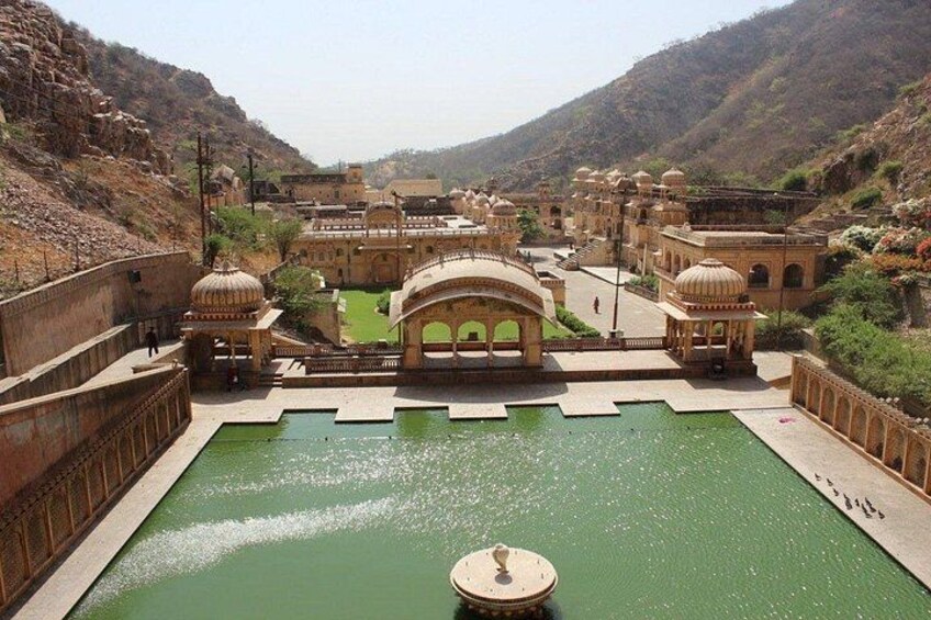 A historical fort with a central water body, surrounded by arched structures and a hilly landscape. 2
