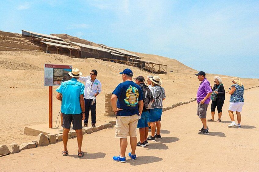 En gruppe mennesker står på en sandsti med et ørkenlandskab og solpaneler i baggrunden. 3
