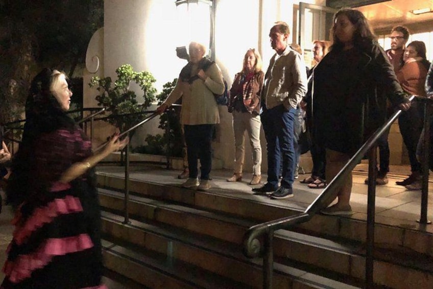A person in a striped dress standing on stairs, a group of people on the steps, and a building in the background. 1