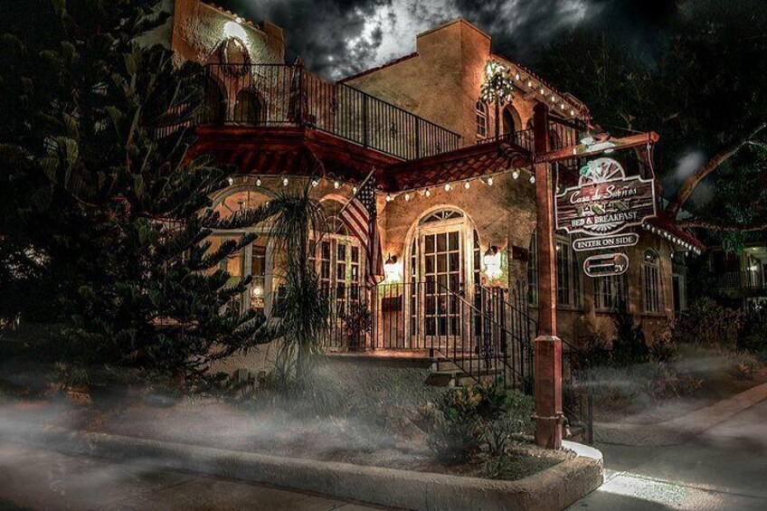 A historic building with arched windows and a balcony, surrounded by trees and a misty atmosphere. 5