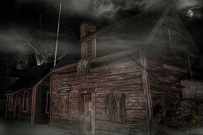 A rustic wooden building with a sign, surrounded by trees and a chain-link fence. 2