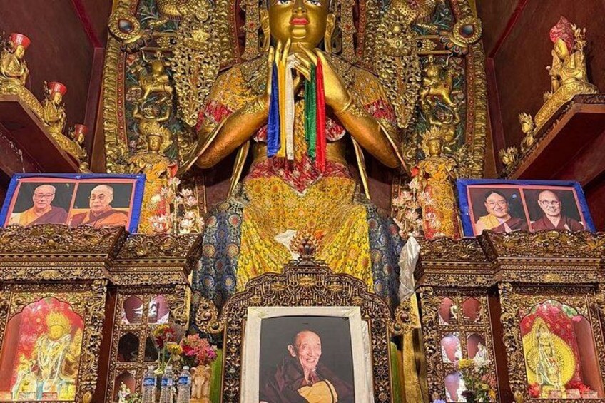 A richly decorated shrine with golden statues, framed portraits, and intricate carvings. 3