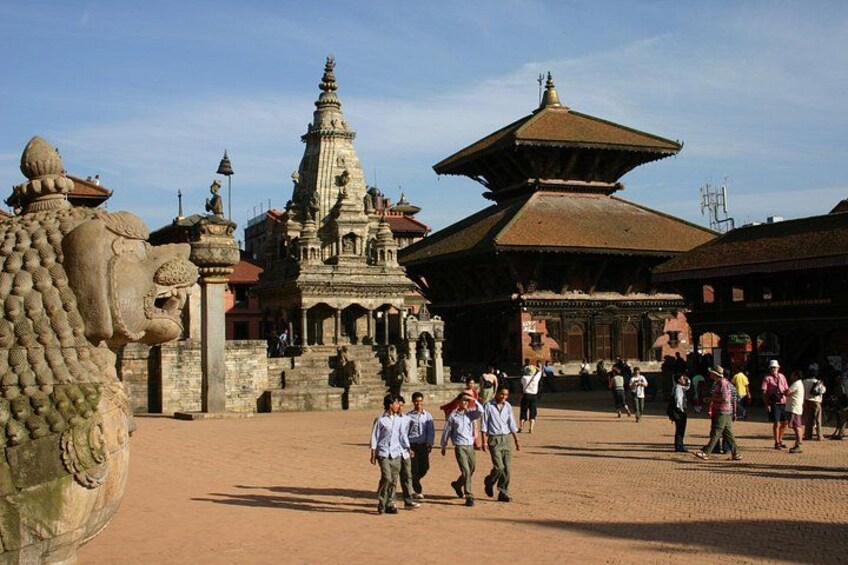 A large stone face, a pagoda-style building, and people walking in a courtyard. 5